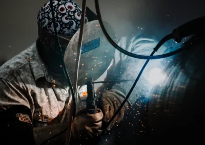 Welder in protective gear with bright sparks flying.